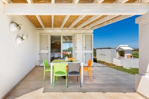 Une terrasse extérieure dotée d’une pergola en bois, d’une table à manger avec des chaises et offrant une vue sur les environs.