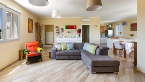 A spacious living area with a large grey sectional sofa, a colorful armchair, and a dining table with chairs. - 2340 Villa Il Neto by Perle di Puglia (Casarano)