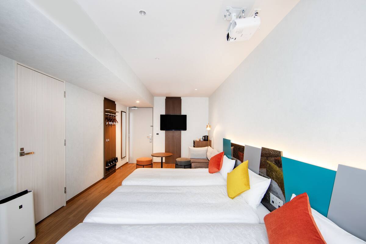 A modern hotel room with a large bed, a TV, a small table, and a closet.
