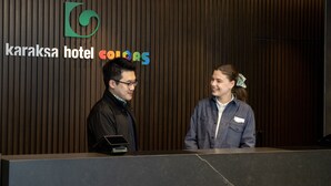 A reception desk at the Karaksa Hotel with a modern design and a vertical wooden panel background. - Karaksa Hotel Colors Tokyo Yaesu (Tokyo)