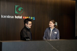 Una recepción en el Hotel Karaksa, con un diseño moderno y un panel de madera vertical de fondo.