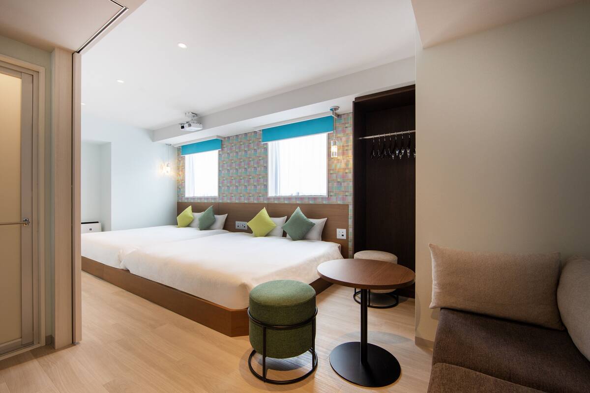 A modern hotel room with a large bed, a small round table, and a sofa.