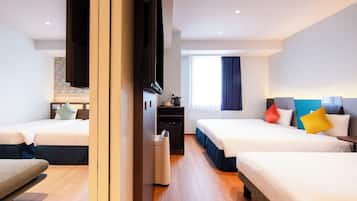A hotel room with two beds, a TV, a small table, and a window with curtains.