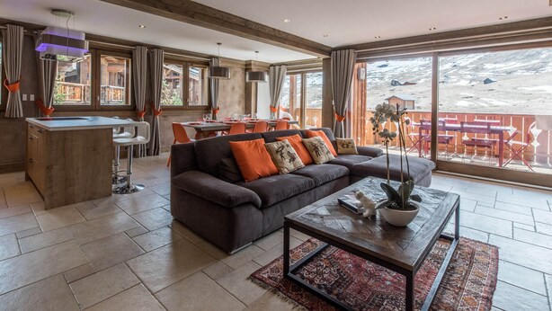 Ein großzügiger Wohnbereich mit einem dunklen Sofa, einem Couchtisch und einem Essbereich mit Stühlen und einem Tisch.