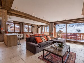 A spacious living area with a sofa, coffee table, and a view of a snowy landscape.