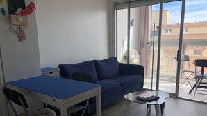 Un salon moderne avec un canapé bleu, une petite table et un fauteuil.