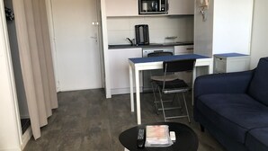Un espace de vie compact comprenant un coin cuisine, une table à manger avec des chaises, un canapé et une petite table basse.