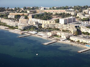 Vue aérienne d’une ville côtière avec un port de plaisance, de nombreux immeubles de grande hauteur et un mélange de bâtiments résidentiels et commerciaux.