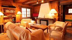 Un intérieur chaleureux de chalet en bois, avec une cheminée, des étagères en bois et des sièges confortables.