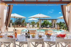 A dining table set for two with a view of a pool and outdoor seating. - 3034 Villetta La Cornola by Barbarhouse (Taurisano)