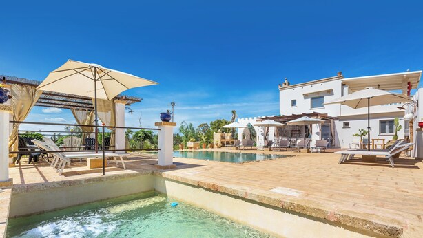 A pool area with lounge chairs and umbrellas, a clear sky, and a building in the background. - 3034 Villetta La Cornola by Barbarhouse (Taurisano)