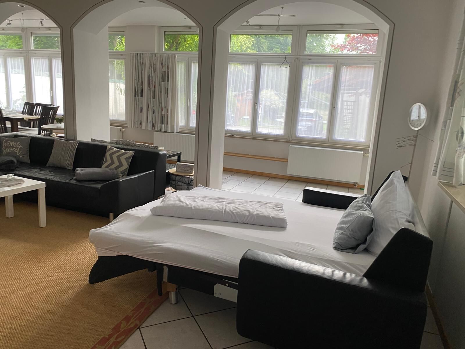 A modern room with a bed, a sofa, and a dining area.
