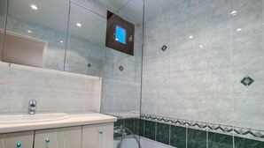 Une salle de bain avec un lavabo blanc, un miroir et un espace douche.