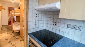 Une cuisine de taille réduite avec un poêle noir, un dosseret de carreaux blancs et des armoires en bois.