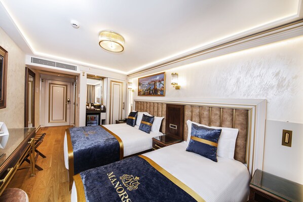 A hotel room with two beds, a desk, and a dining table. - Manors Hotel Old City (Istanbul)