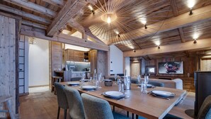 Un vaste espace dédié à la salle à manger, avec une longue table en bois dressée pour le repas, entourée de chaises rembourrées.