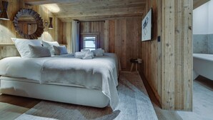 Un intérieur en bois comprenant un lit, un miroir et un tableau encadré.