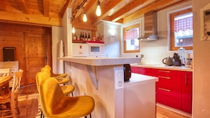 A kitchen with wooden beams, a white countertop, red cabinets, and a bar area with yellow chairs. - Renovated apartment, 3 bedrooms, pets allowed, parking, close to Grand Massif (Morillon Village)