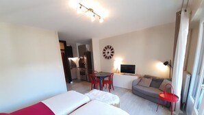 A room with a bed, a sofa, a TV, and a dining area with chairs and a table. - Renovated studio in the center for 2 people (Brides-les-Bains)