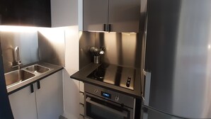 A compact kitchen with a stainless steel refrigerator, a built-in oven, and a sink. - Renovated studio in the center for 2 people (Brides-les-Bains)
