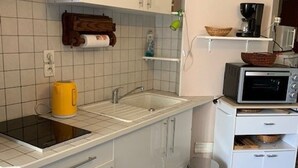 Une cuisine compacte équipée d’un évier, d’une bouilloire, d’un four à micro-ondes et d’une petite poubelle.