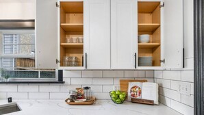 Une cuisine moderne avec des armoires blanches, un plan de travail en marbre et un lave-vaisselle encastré.
