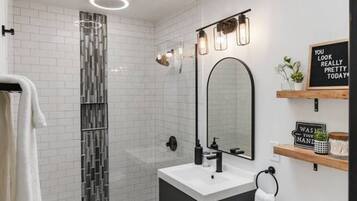 A modern bathroom with a skylight, a glass shower enclosure, a white sink, and a toilet.