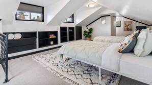 Une chambre avec un plafond de style industriel, un lit, une table de chevet, une commode et des étagères intégrées.