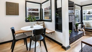 Un salon moderne avec une table à manger ronde, des chaises noires, une cheminée et de grandes fenêtres.