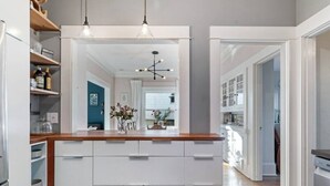 Une cuisine moderne avec des meubles blancs, un plan de travail en bois et des luminaires suspendus.
