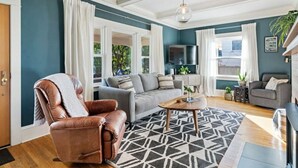 Un salon moderne avec un fauteuil en cuir, un canapé gris et une table basse.