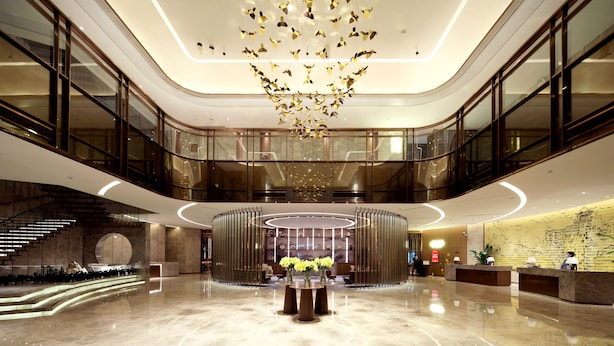 Un'ampia hall con una reception centrale, un lampadario e una scala.