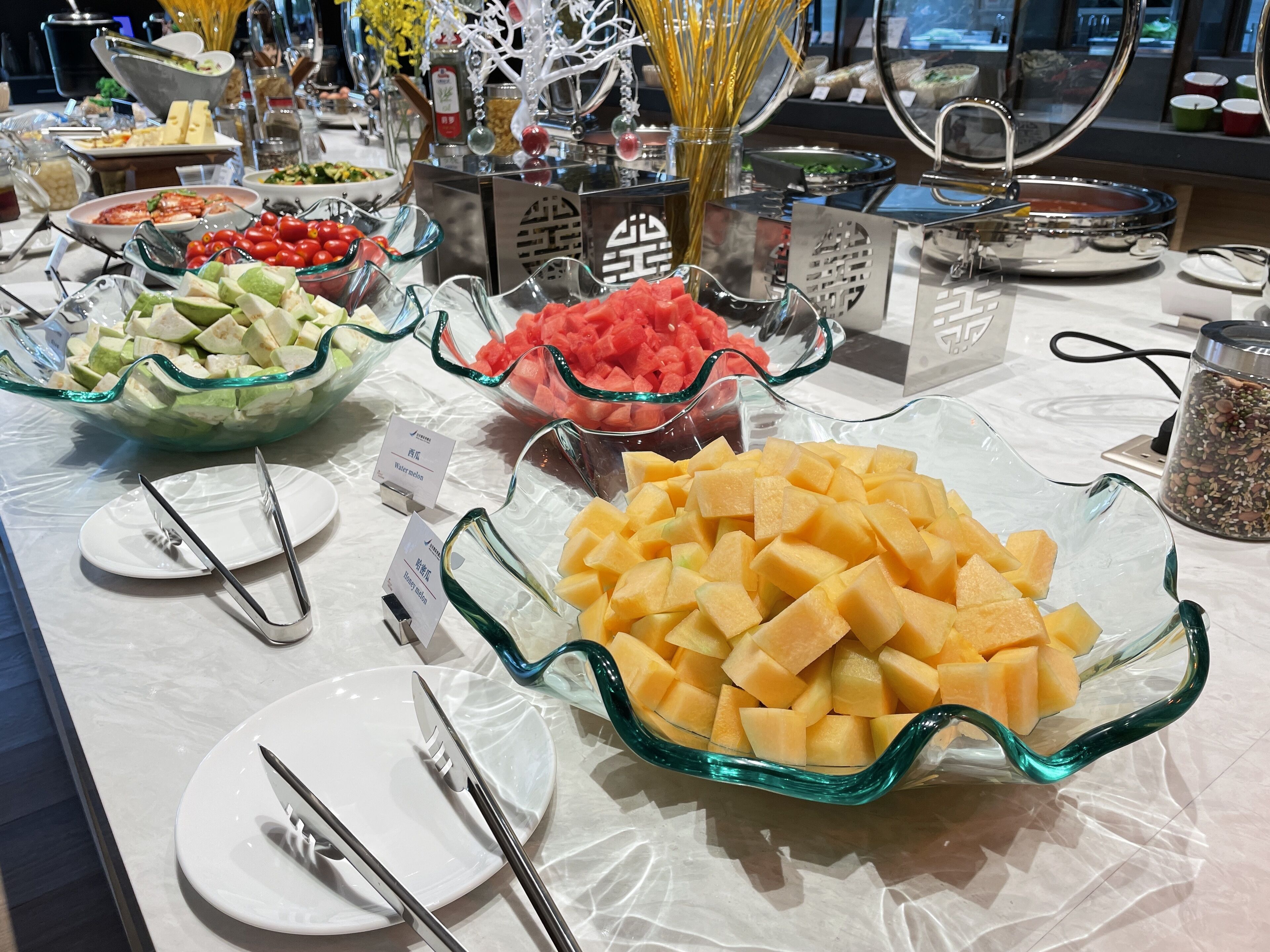 A buffet table with various food items including watermelon, cantaloupe, and other fruits.