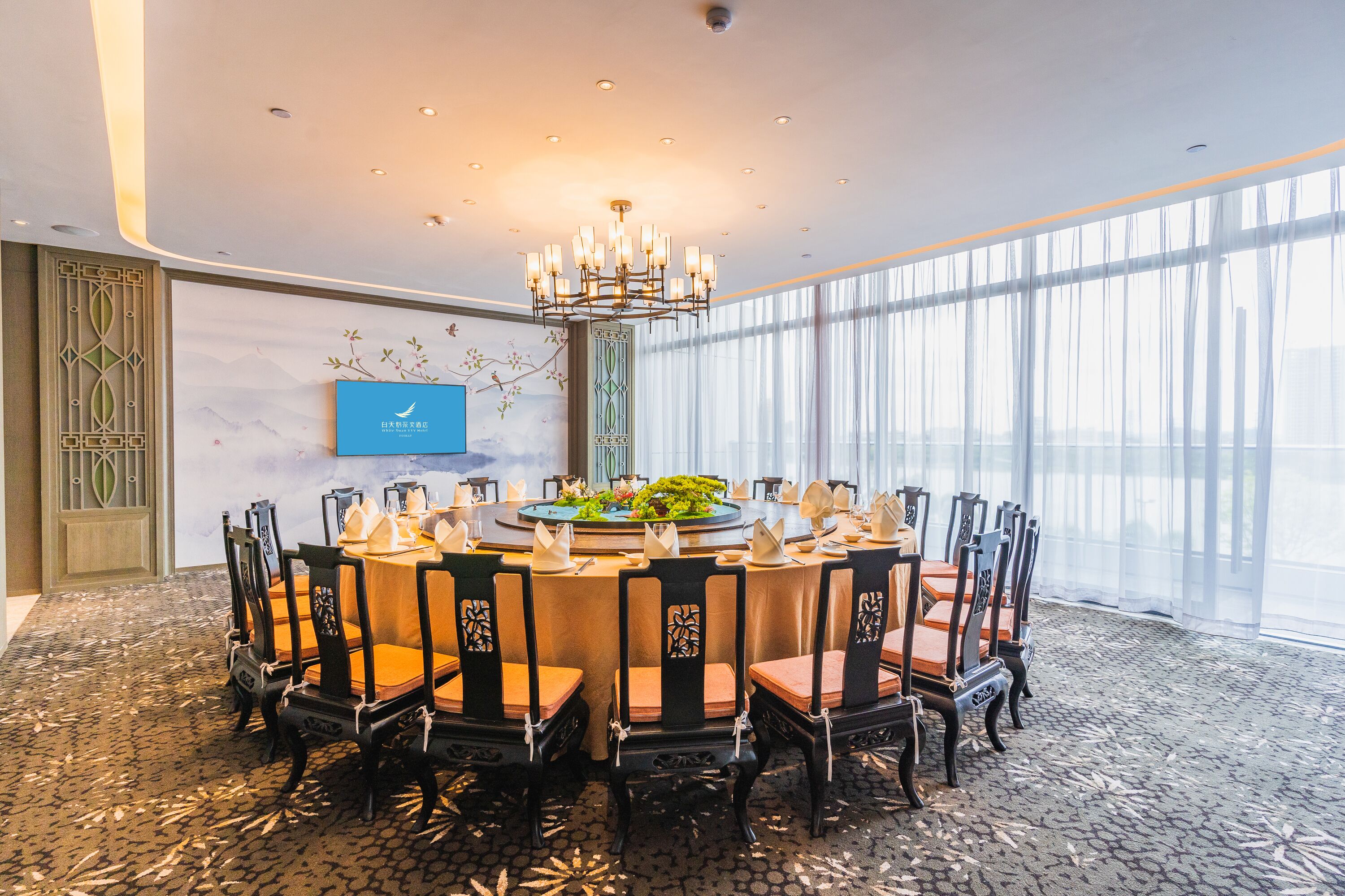 A conference room with a round table, chairs, and a chandelier.