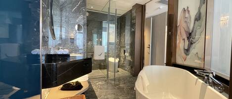 Une salle de bain moderne avec une grande baignoire, une douche à l’italienne et un meuble-lavabo en marbre.