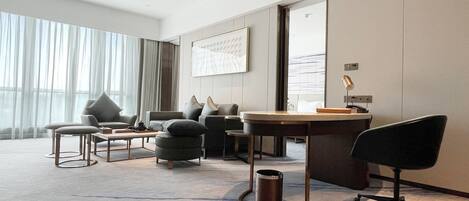 Une chambre d’hôtel moderne dotée d’une grande fenêtre, d’un canapé, d’un bureau et d’une chaise.