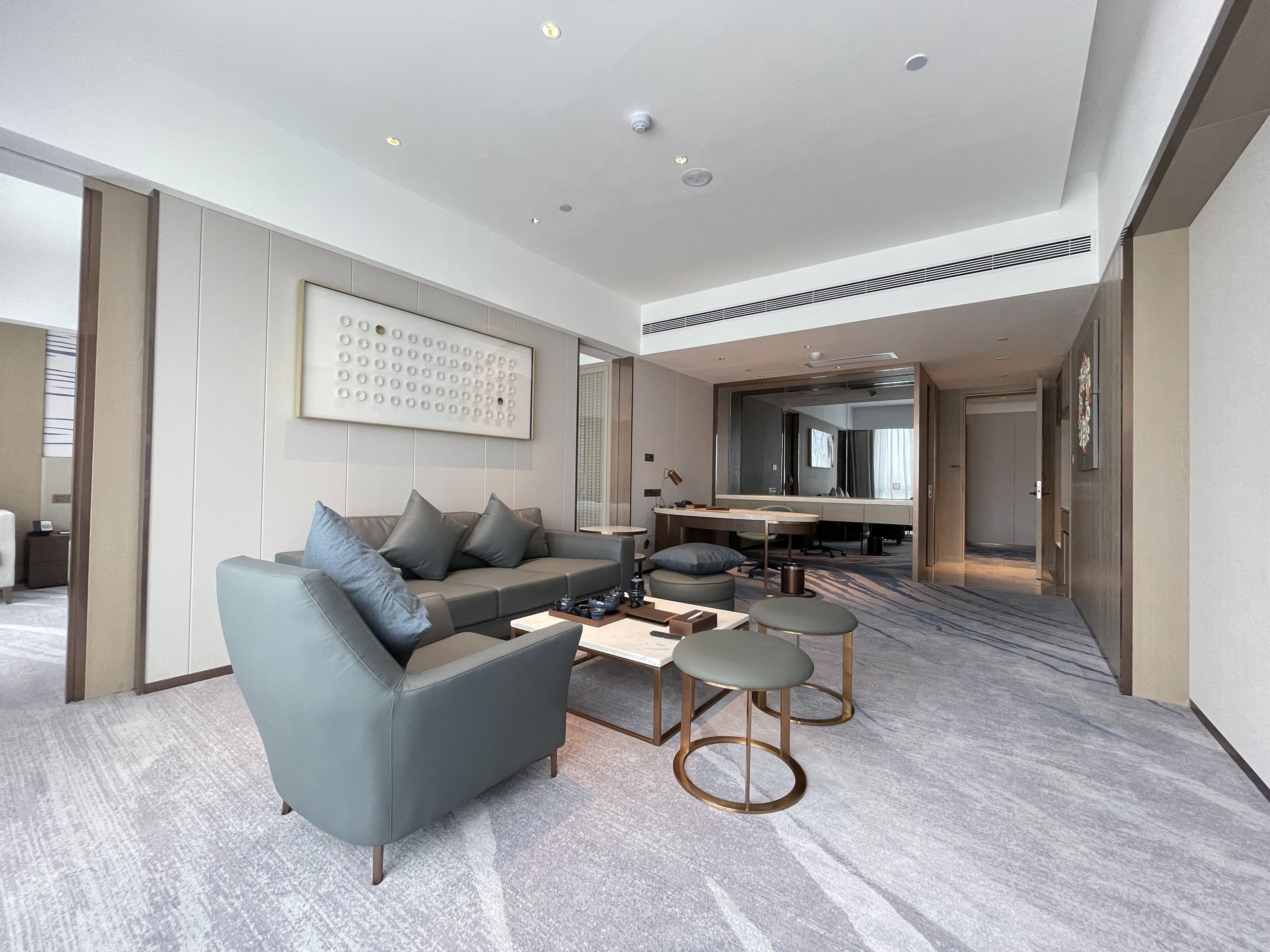 Ein modernes Hotelzimmer mit grauem Sofa, einem Couchtisch und einem Schreibtisch mit Stuhl.