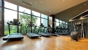 Una palestra con tapis roulant, ellittiche e cyclette, ampie finestre e pavimento in legno.