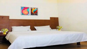 Un lit bien fait, avec du linge de lit blanc, une tête de lit en bois et deux tableaux accrochés au mur.
