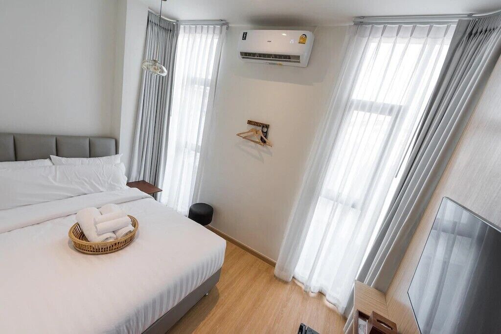 Een hotelkamer met een bed, een wandairconditioner, een klein tafeltje en een televisie.