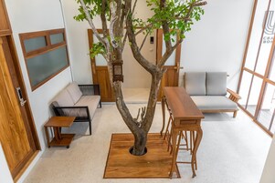 Una habitación con un centro de mesa con forma de árbol de madera, un sofá, una mesita y un banco de madera.