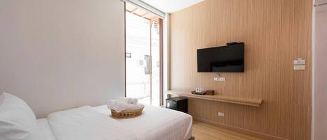 A modern hotel room with a bed, a television mounted on the wall, and a wooden panel wall.