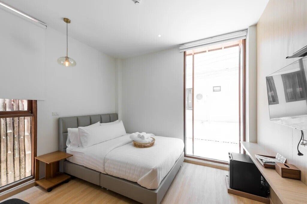 A modern bedroom with a bed, a TV, and a window.