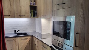A modern kitchen with wooden cabinets, a stainless steel oven, and a built-in microwave. - High quality apartment in the heart of the French Alps - 5 minutes from ski lift (Brides-les-Bains)