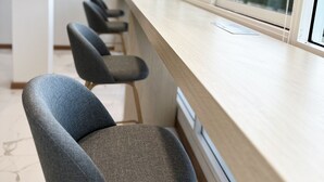 Un interior moderno con una encimera larga y tres sillas tapizadas grises con patas de madera.