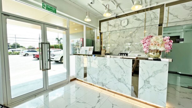 Zona de recepción de un hotel con mostrador de mármol, un reloj y un letrero que dice 'Solo para empleados'.