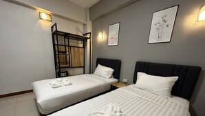 Habitación de hotel con dos camas, un armario de madera y lámparas fijadas a la pared.