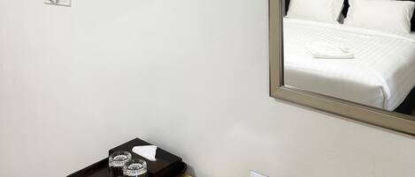 A hotel room with a bed, a TV mounted on the wall, a tray with glasses and a napkin, and a sign with WiFi details.