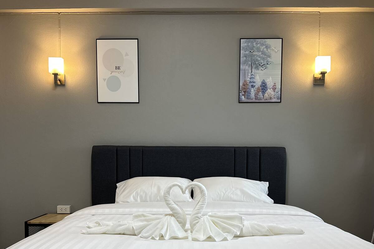 Habitación de hotel con una cama grande, dos lámparas de pared y dos cuadros en la pared.