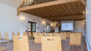 Un salón de conferencias con sillas de madera, una pantalla de proyector mostrando 'Domaine du Marquenterre' y un candelabro.